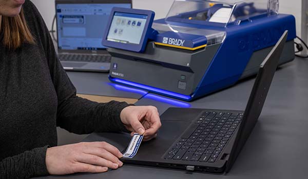 En medarbetare applicerar en resurstagg på en bärbar dator.