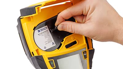 En rulle med etikettmaterial laddas i en M710-skrivare.