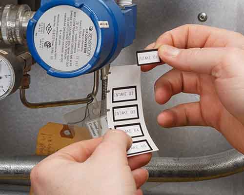 En person som applicerar M610-utskrivna etiketter på en maskin.