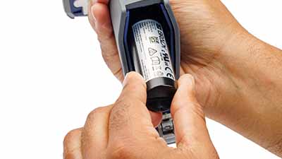 En person som sätter in ett batteri i skannerns handtag.